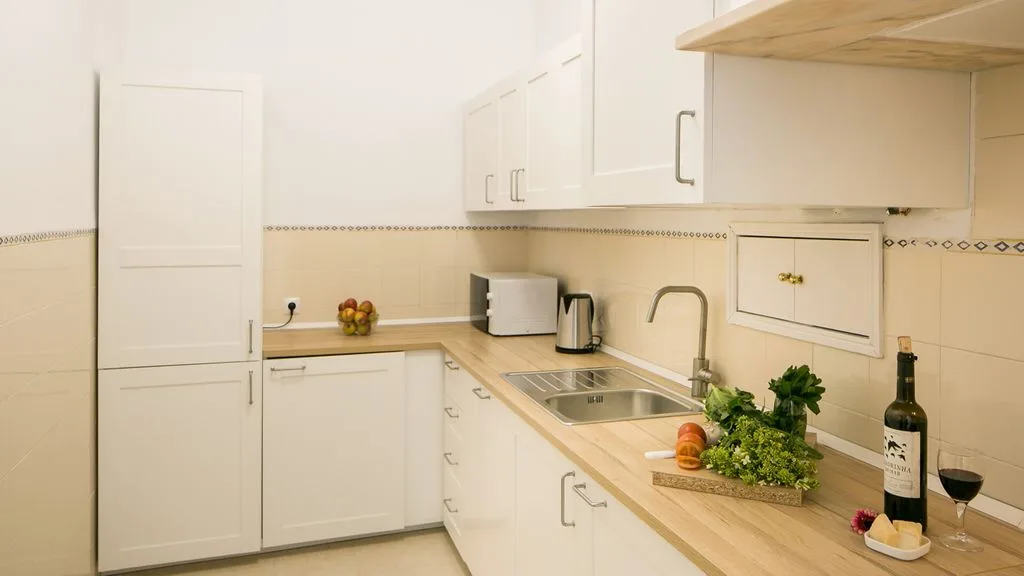 Una cocina luminosa con armarios blancos y un fregadero sobre la encimera.