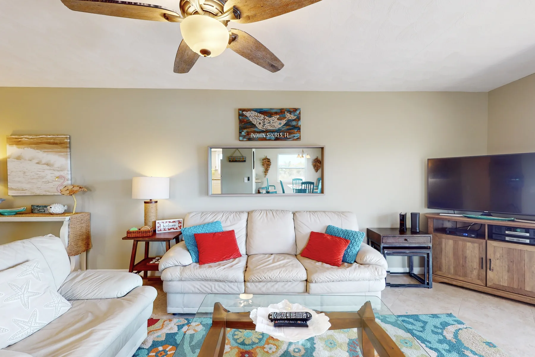A living room with a white sofa, colorful cushions, and a television.