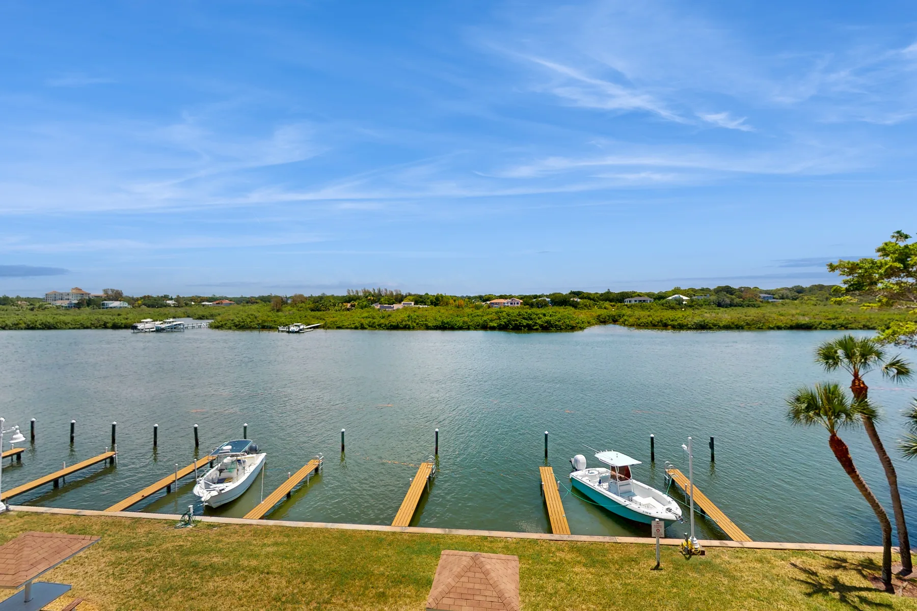 A waterfront scene with boat docks along a calm inlet and greenery across the water.