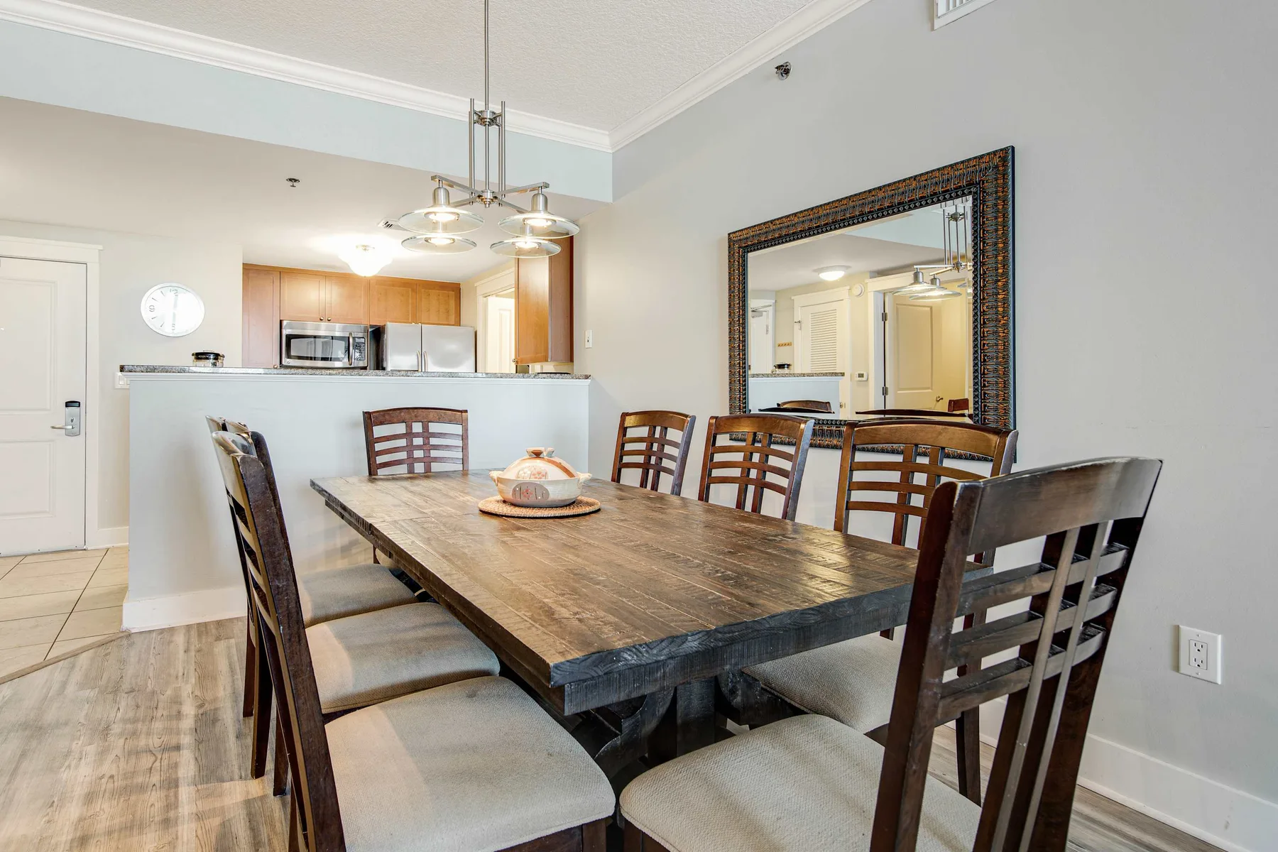 A dining area features a long wooden table and cushioned seating.