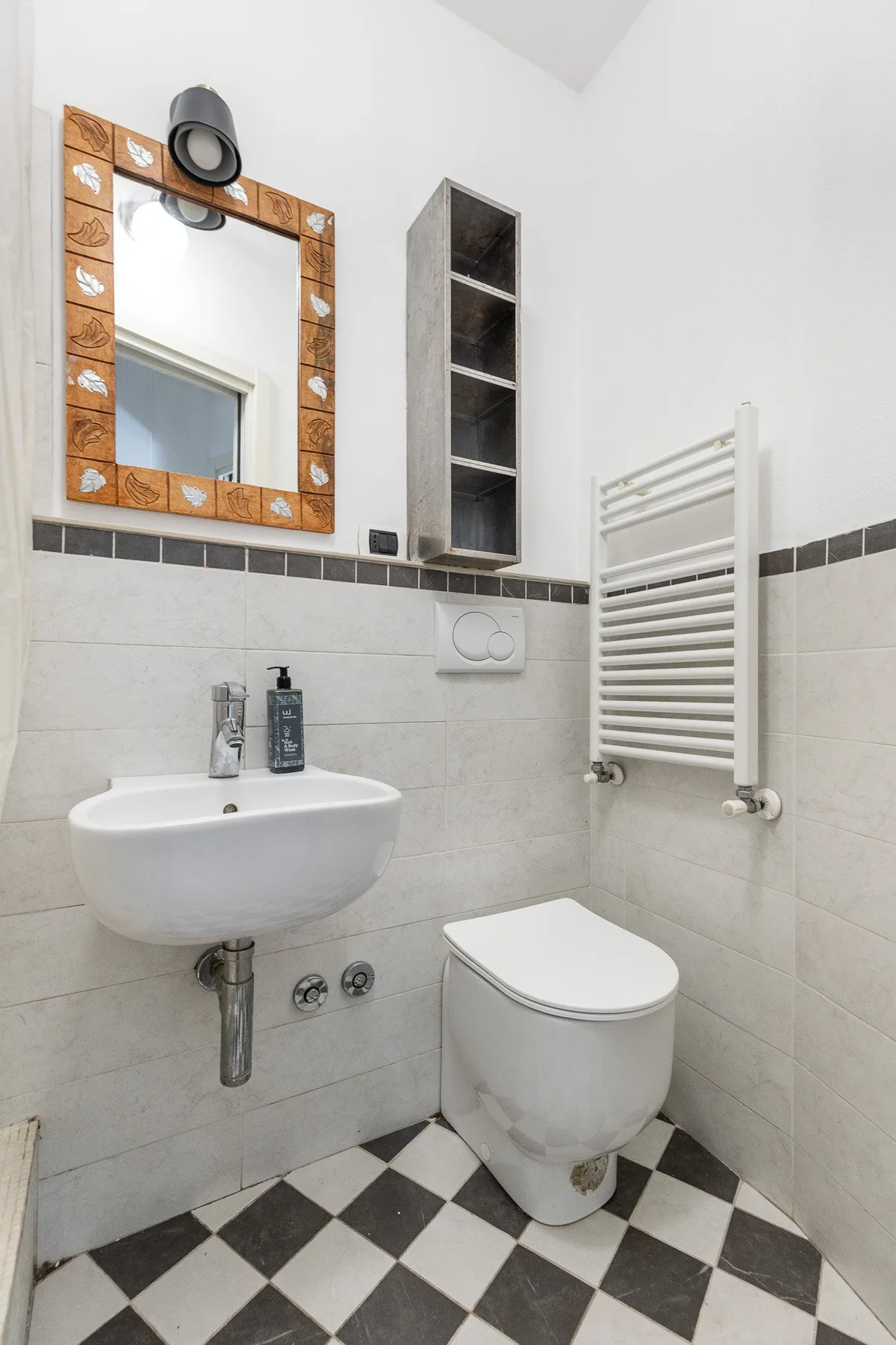 A bathroom with a wall-mounted sink, toilet, and checkered floor.