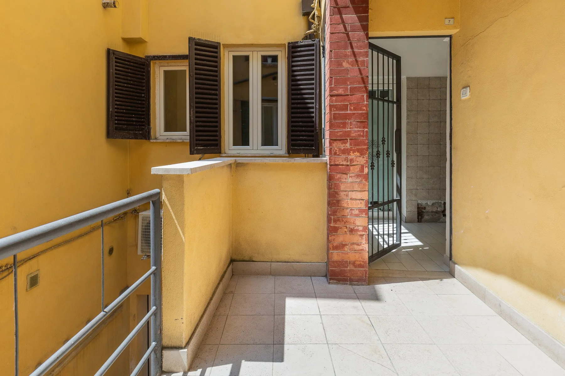 A yellow-walled terrace with shuttered windows and an open doorway.