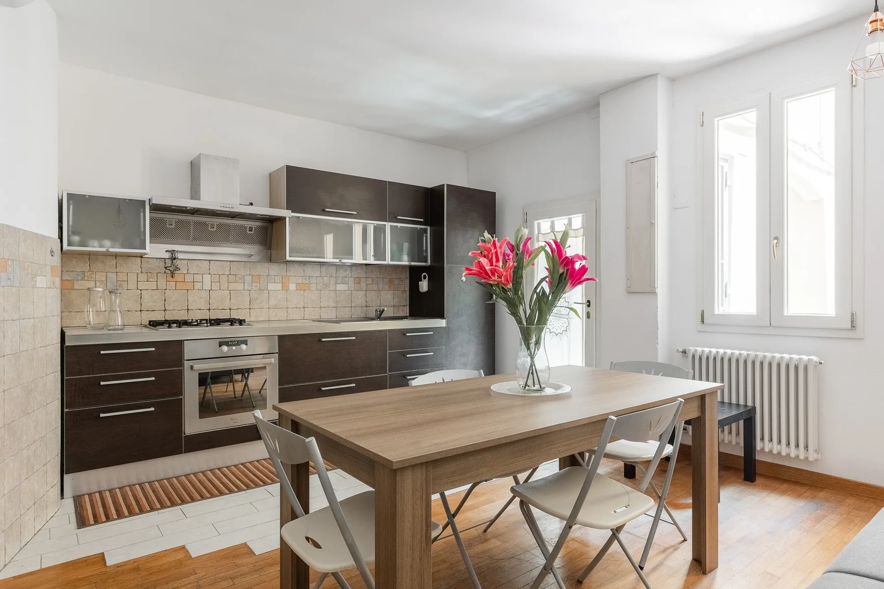 Una cocina y comedor con gabinetes oscuros y una mesa de madera.