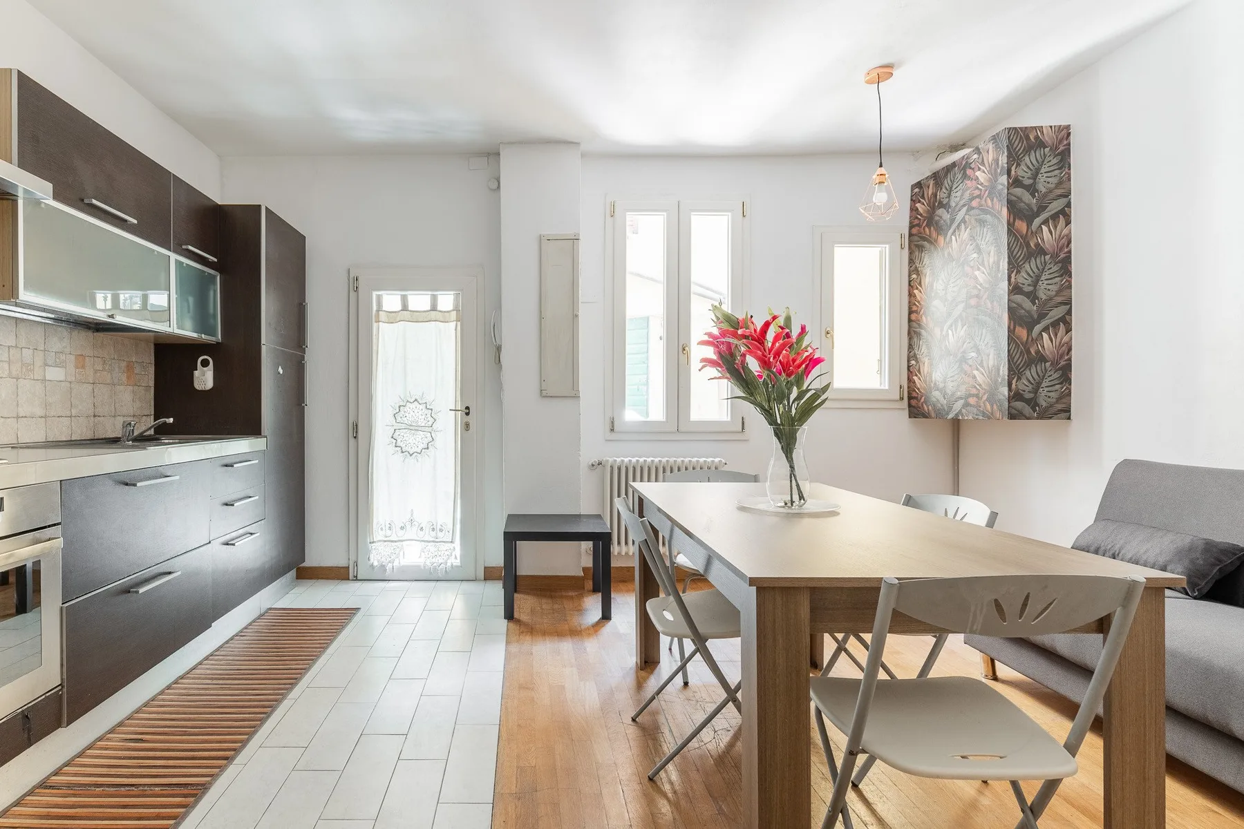 Una luminosa cocina con comedor, mesa, sillas y armarios oscuros.