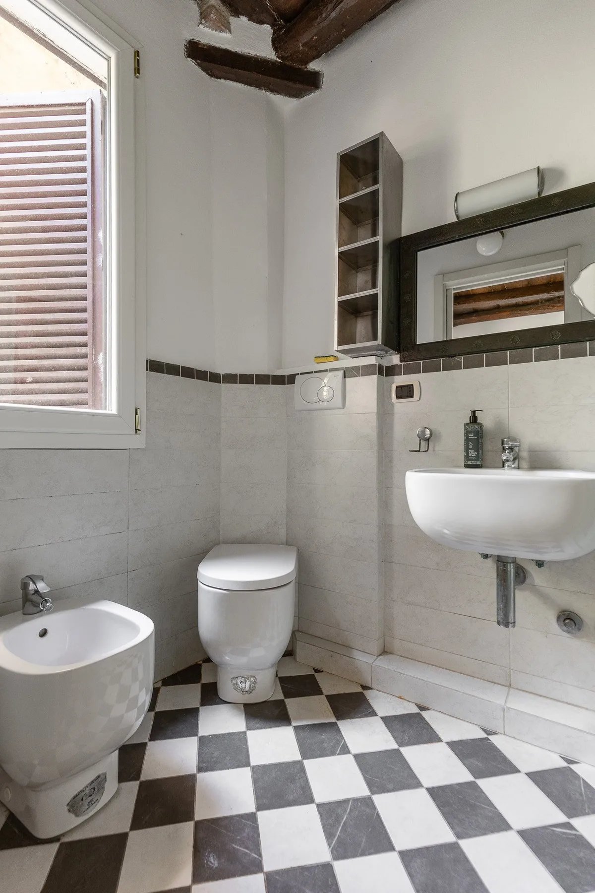A tiled bathroom with a toilet, sink, and checkerboard floor.