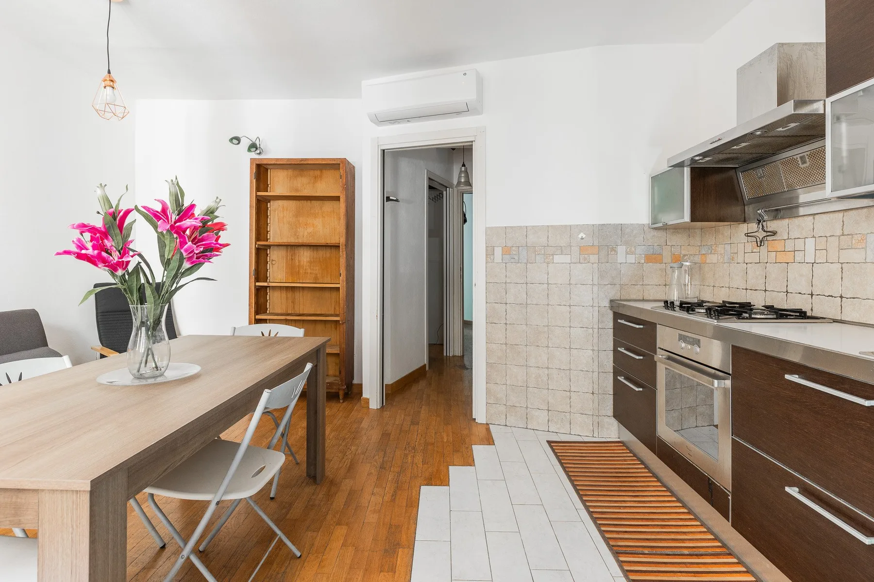 A bright kitchen and dining area with a wooden table and built-in cabinets.