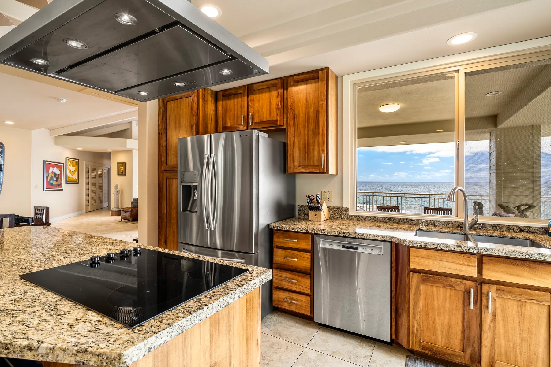 Una cocina con gabinetes de madera, electrodomésticos de acero inoxidable y una ventana amplia con vista al agua.