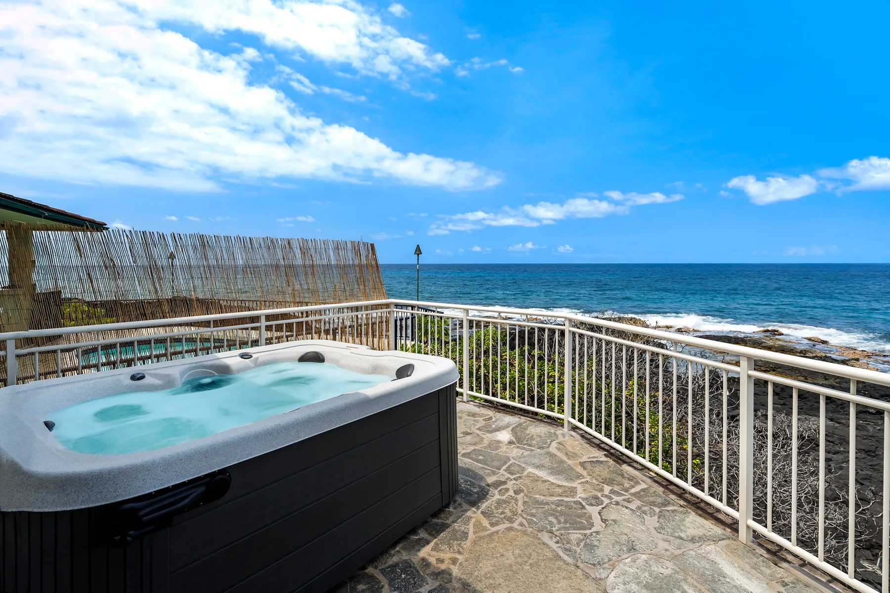 Un patio junto al mar con una bañera de hidromasaje y vista al océano.