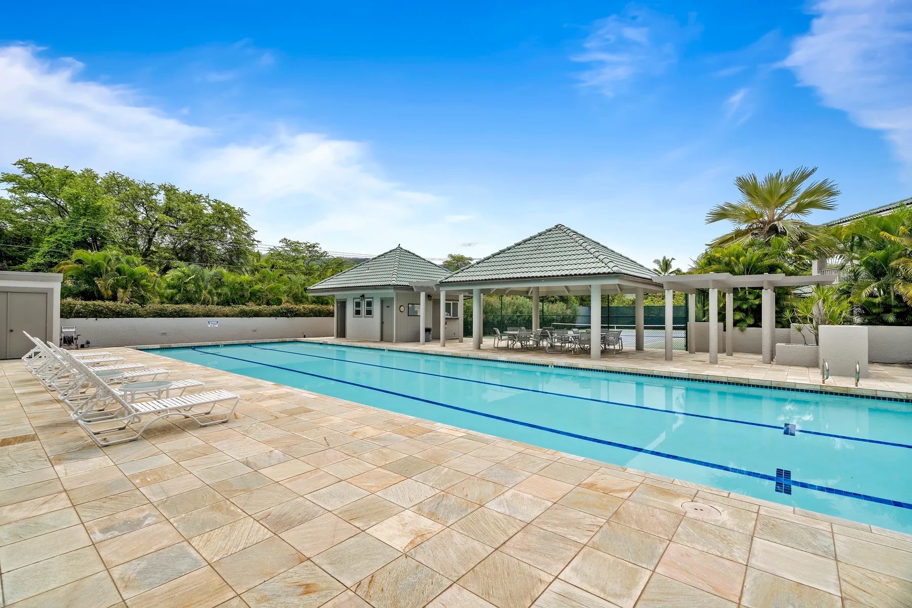 Piscina al aire libre junto a una terraza pavimentada y una zona de descanso cubierta.