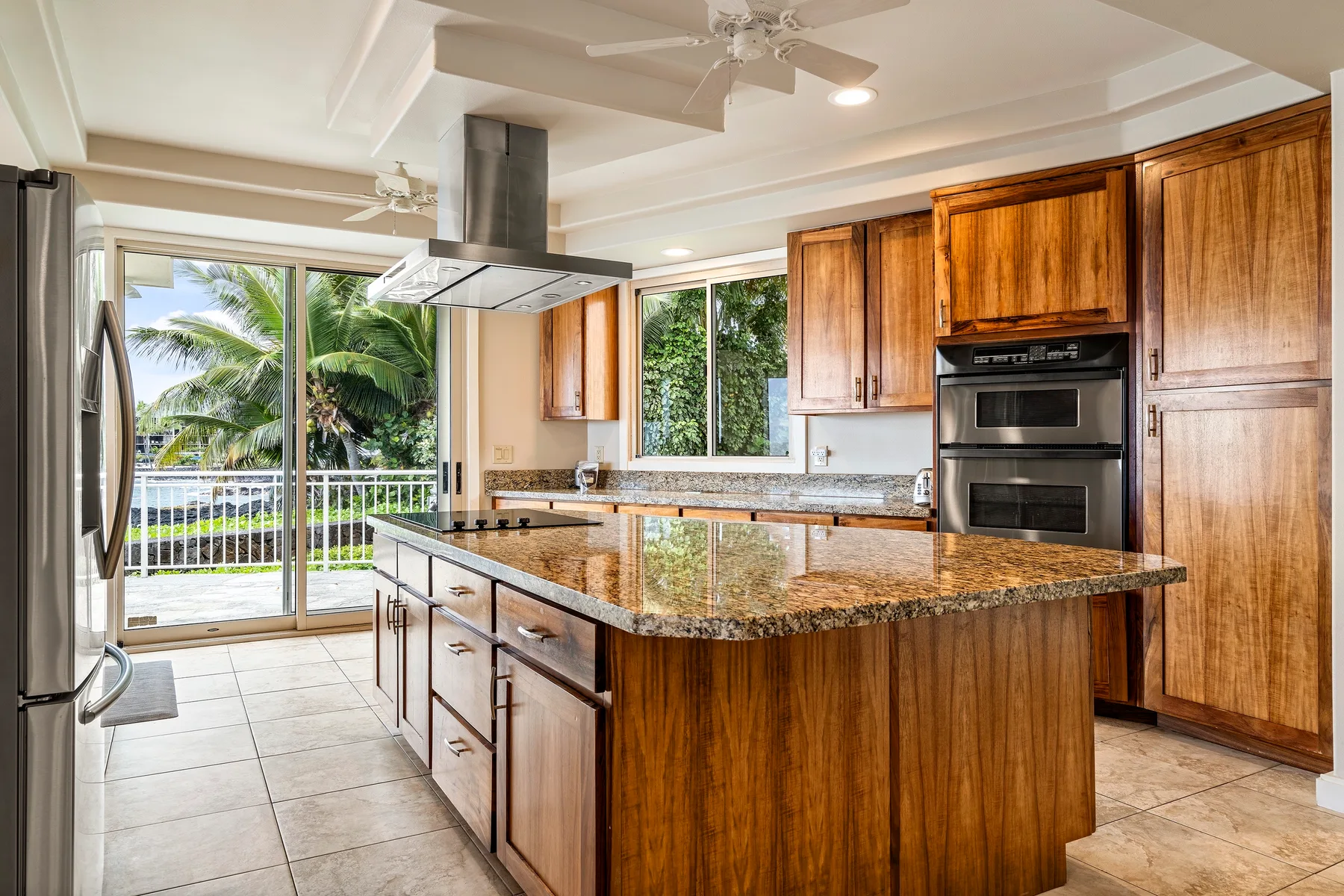 Una cocina amplia con una isla central, gabinetes de madera y puertas corredizas de vidrio.