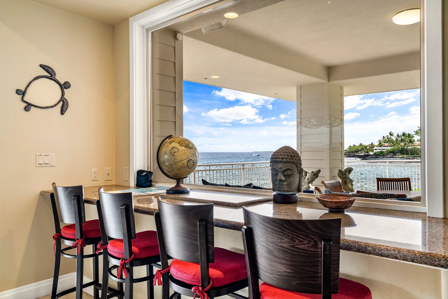 Un comedor con una barra y sillas de asiento rojo junto a una amplia vista al mar.