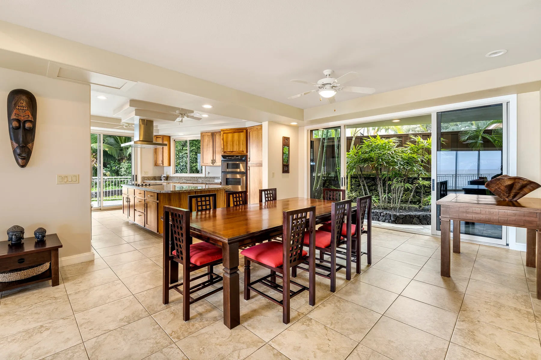Un comedor con una mesa de madera y sillas junto a la cocina y grandes ventanas.