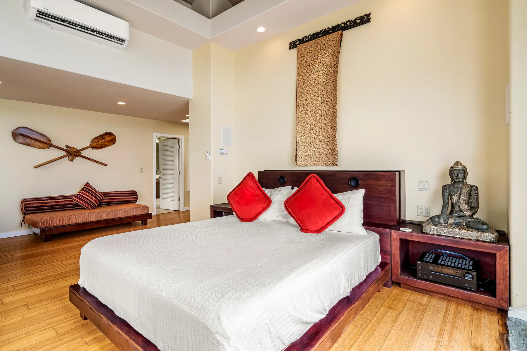 Un dormitorio con una cama grande, muebles de madera y un aire acondicionado en la pared.