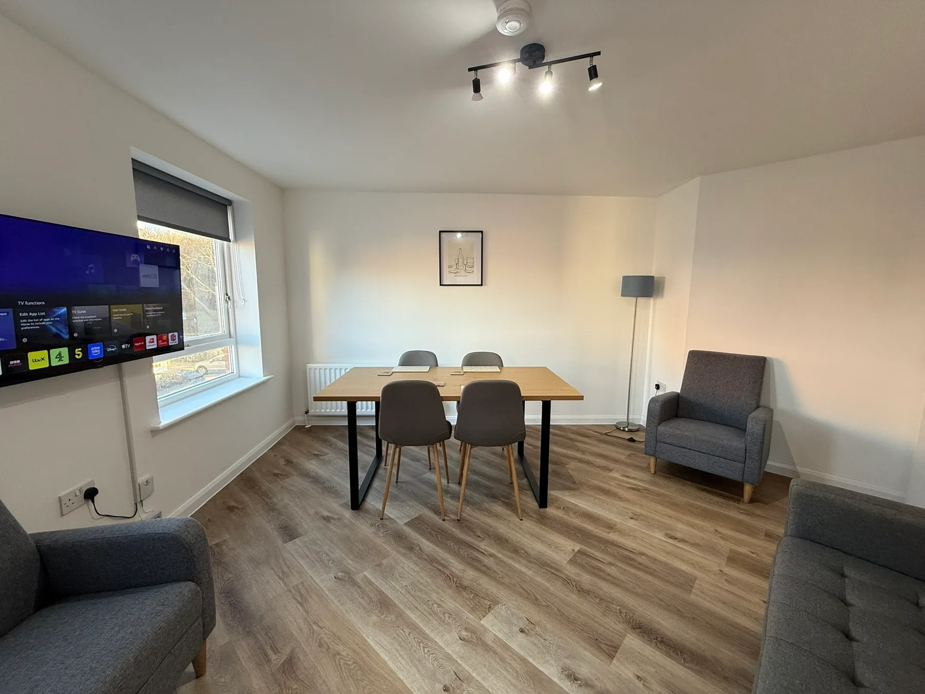 Comedor con mesa y sillas, asientos y un televisor montado en la pared.