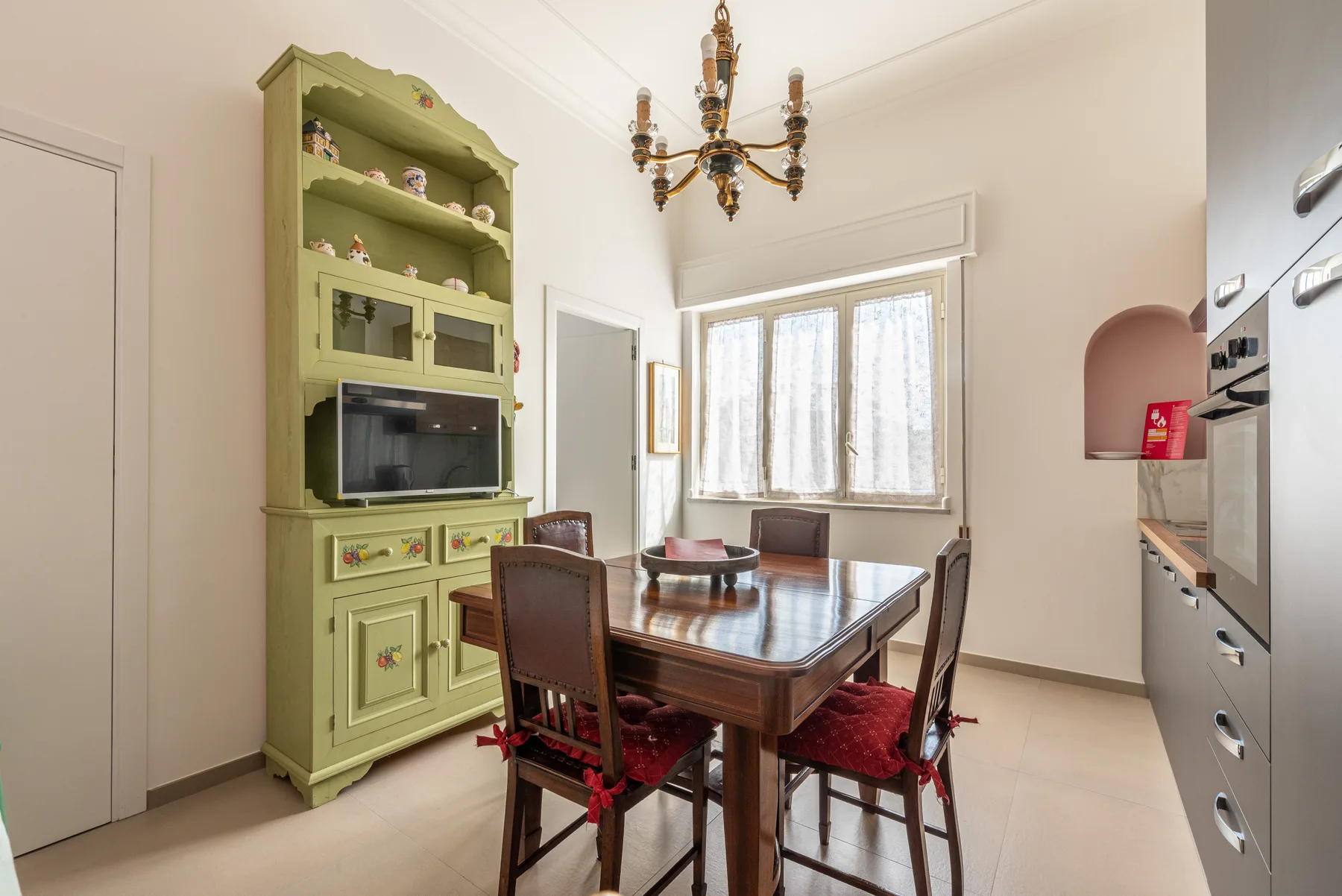 A dining area with a wooden table, chairs, and a green built-in cabinet.