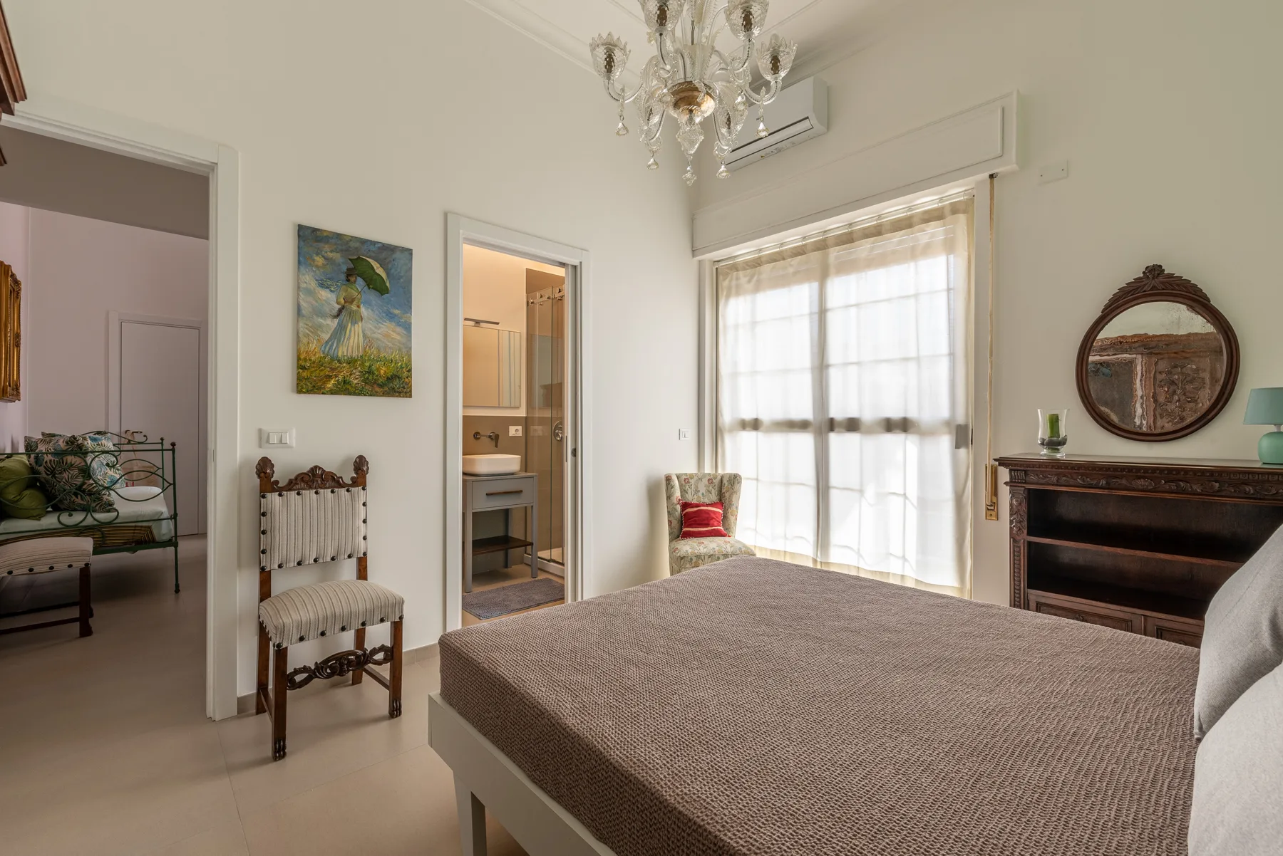A bedroom with a large bed, a bright window, and an open doorway.