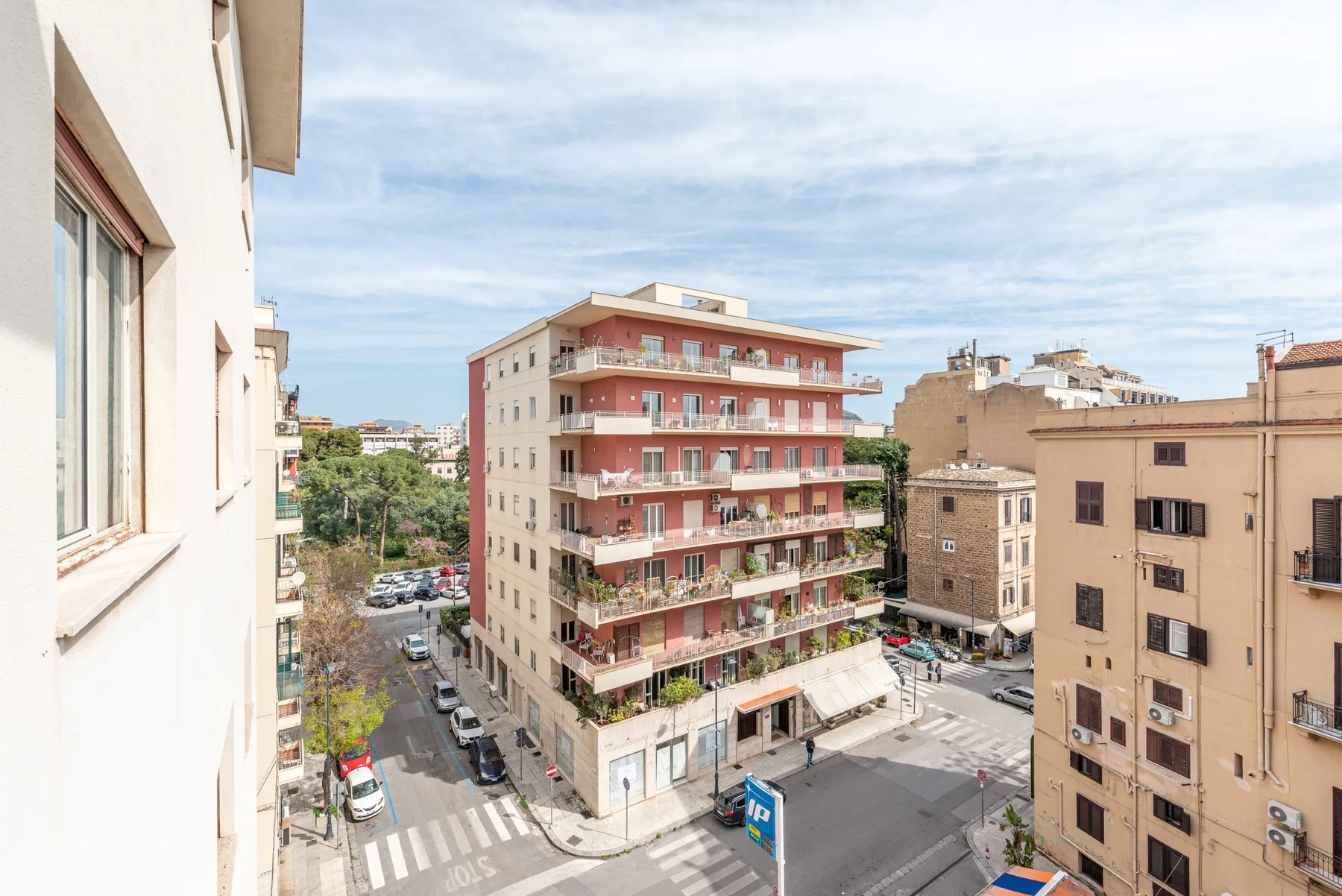 City street scene with apartment buildings, balconies, and a pedestrian crossing.