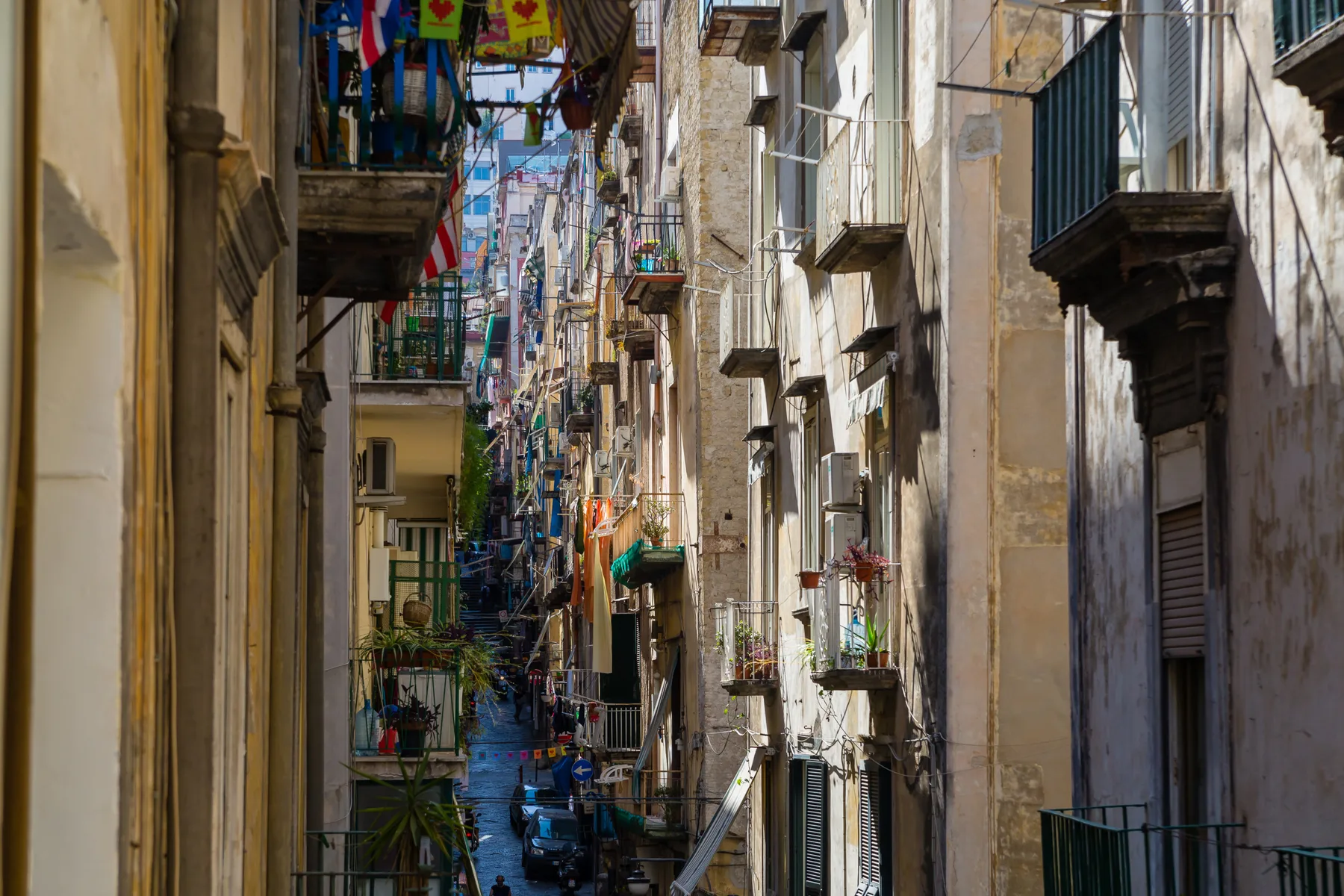 Una calle urbana estrecha flanqueada por edificios altos y balcones.