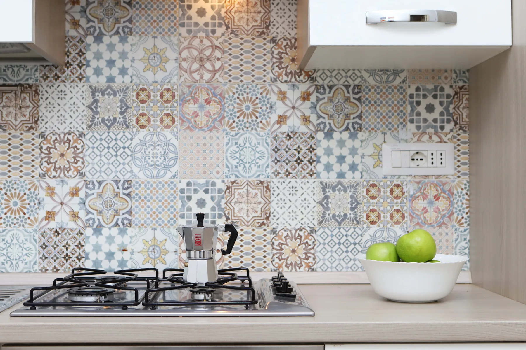 Una encimera de cocina con una estufa de gas y un salpicadero de azulejos coloridos.