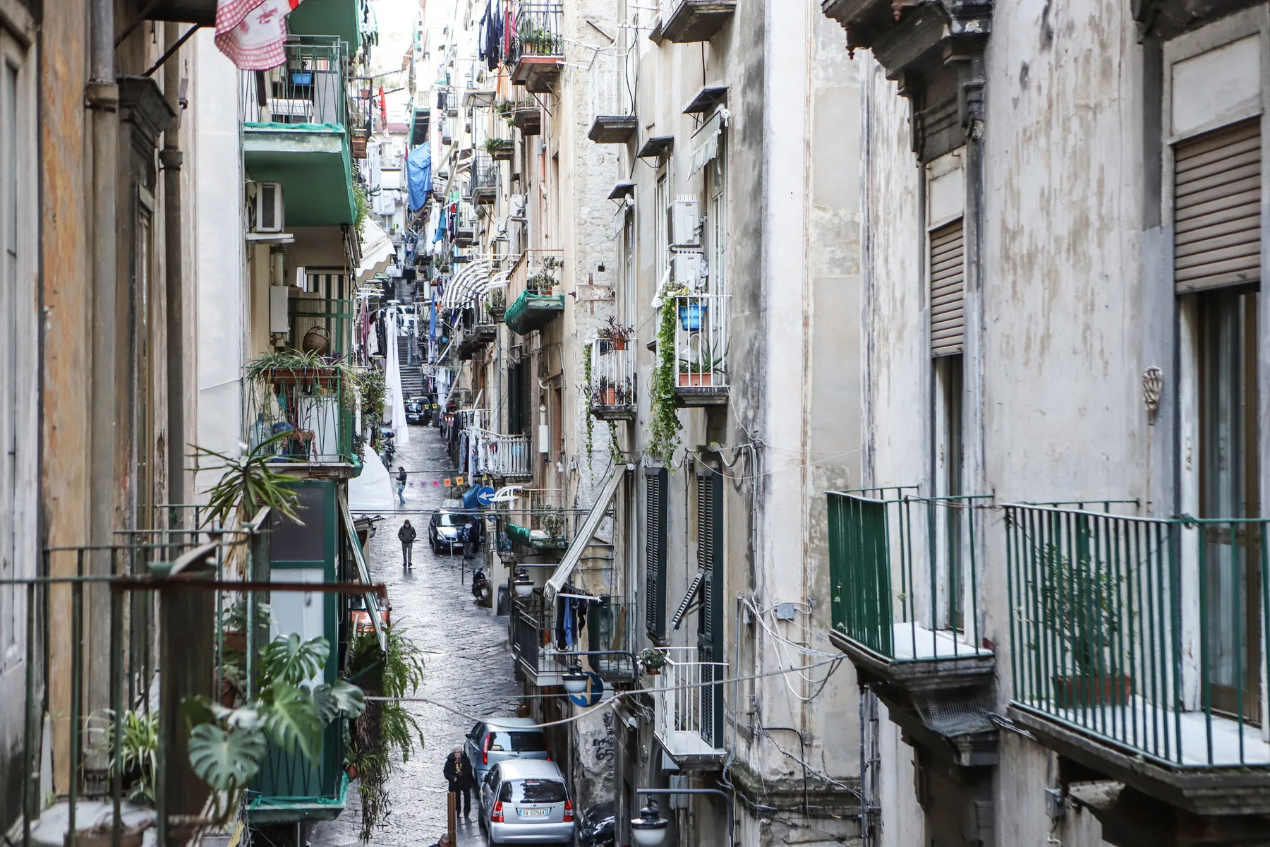 Una calle urbana estrecha, flanqueada por edificios muy juntos y balcones.