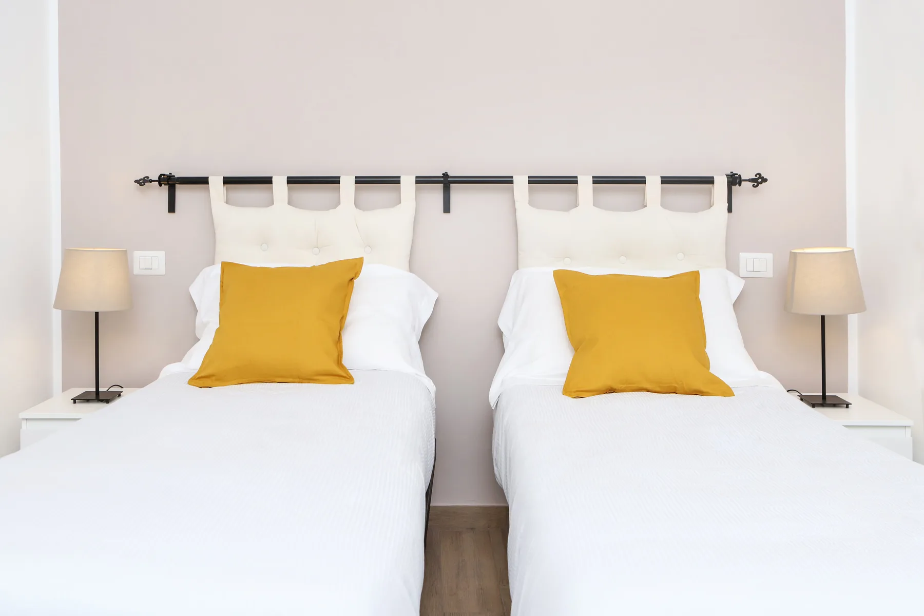 Un dormitorio con dos camas, cada una con una almohada color mostaza.