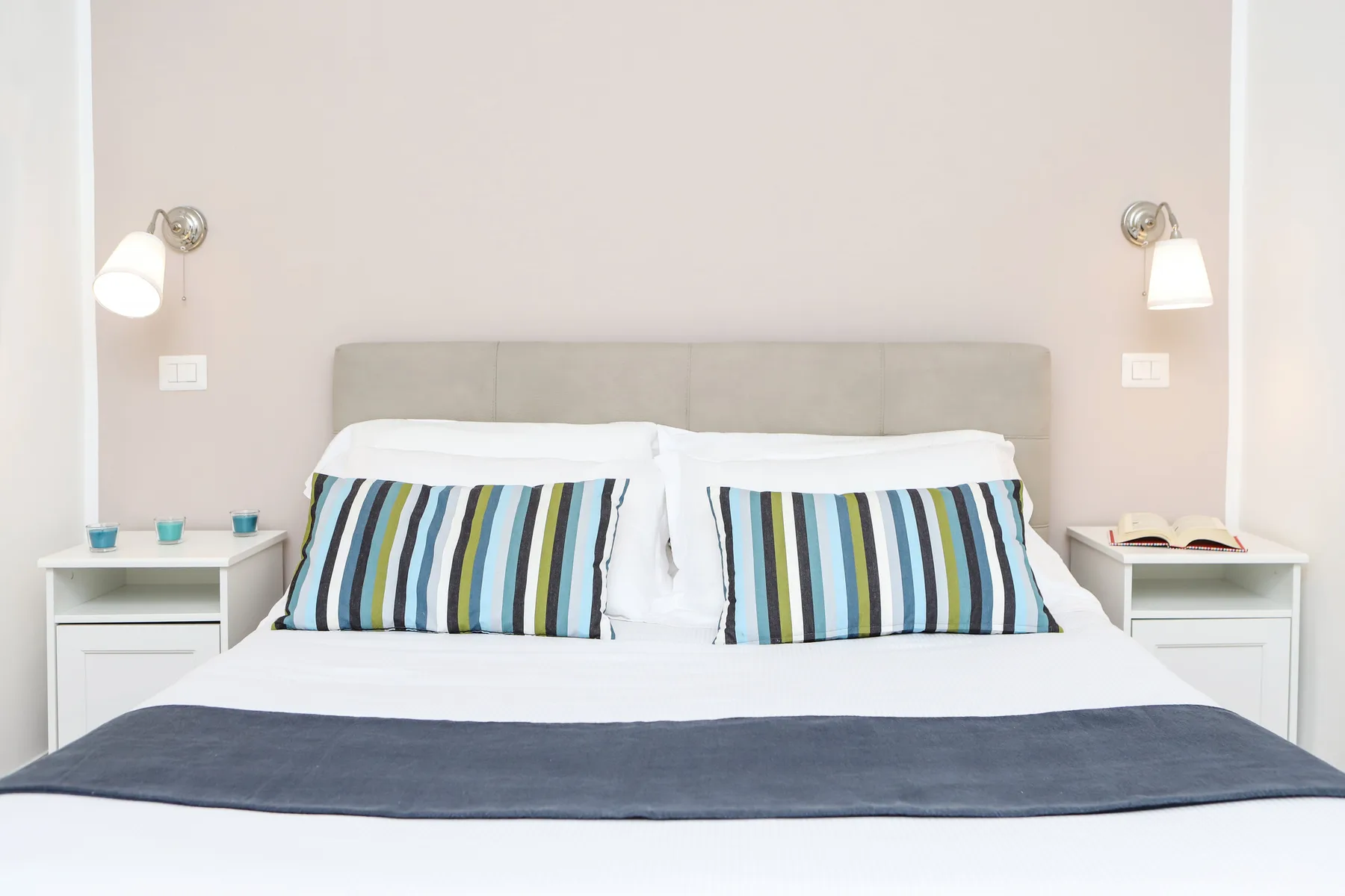 Un dormitorio con una cama tendida y almohadas a rayas.