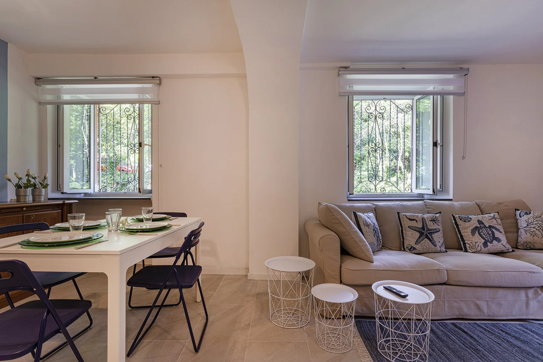 Una luminosa sala de estar y comedor con mesa, asientos y grandes ventanas.