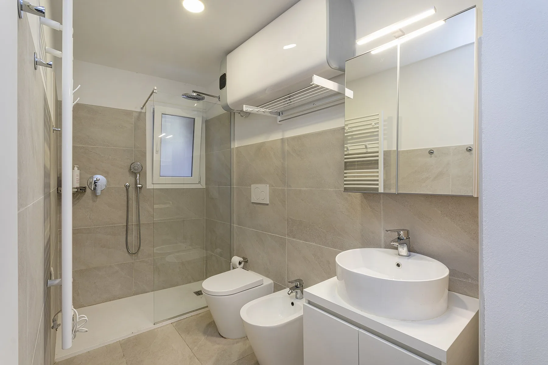 A tiled bathroom with a sink, toilet, and glass shower.