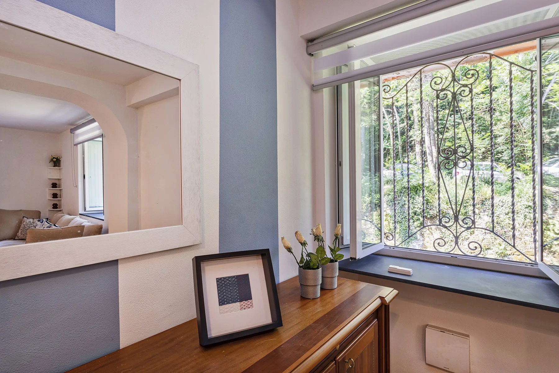 A bright interior window nook with decorative metal bars and a wooden console.