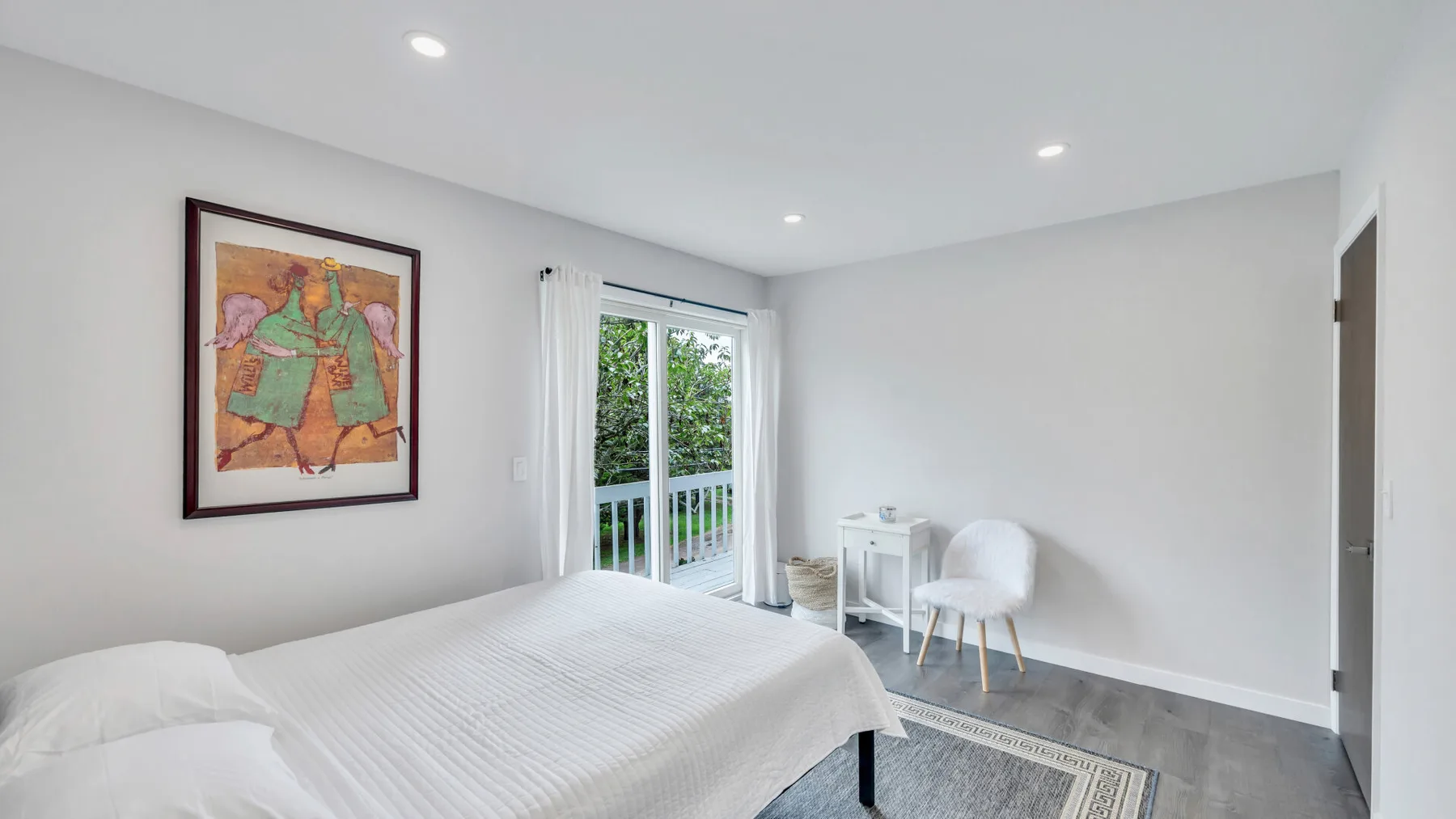 Un dormitorio luminoso con una cama junto a puertas de vidrio que dan a un balcón.