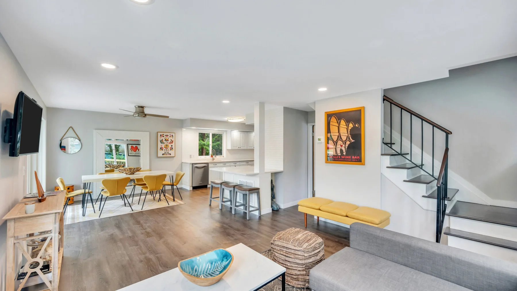 Un espacio abierto de sala y comedor con una isla de cocina y una escalera.