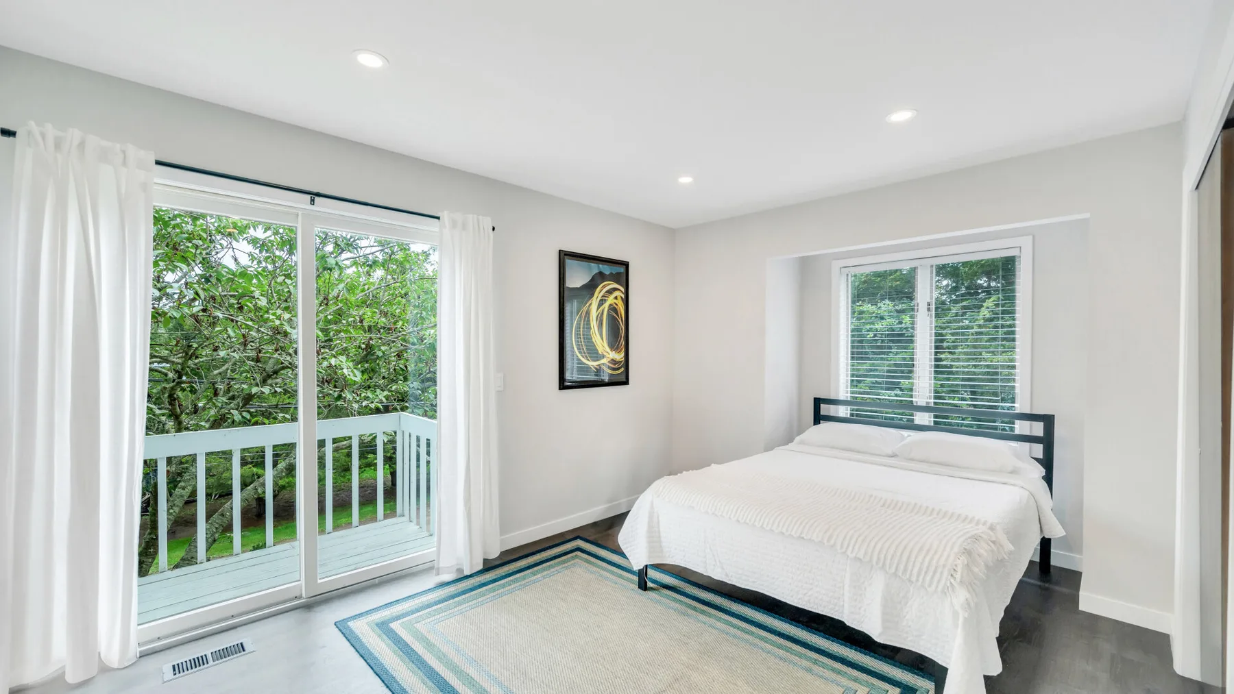 Un dormitorio luminoso con una cama tendida y puertas corredizas de vidrio hacia un balcón.