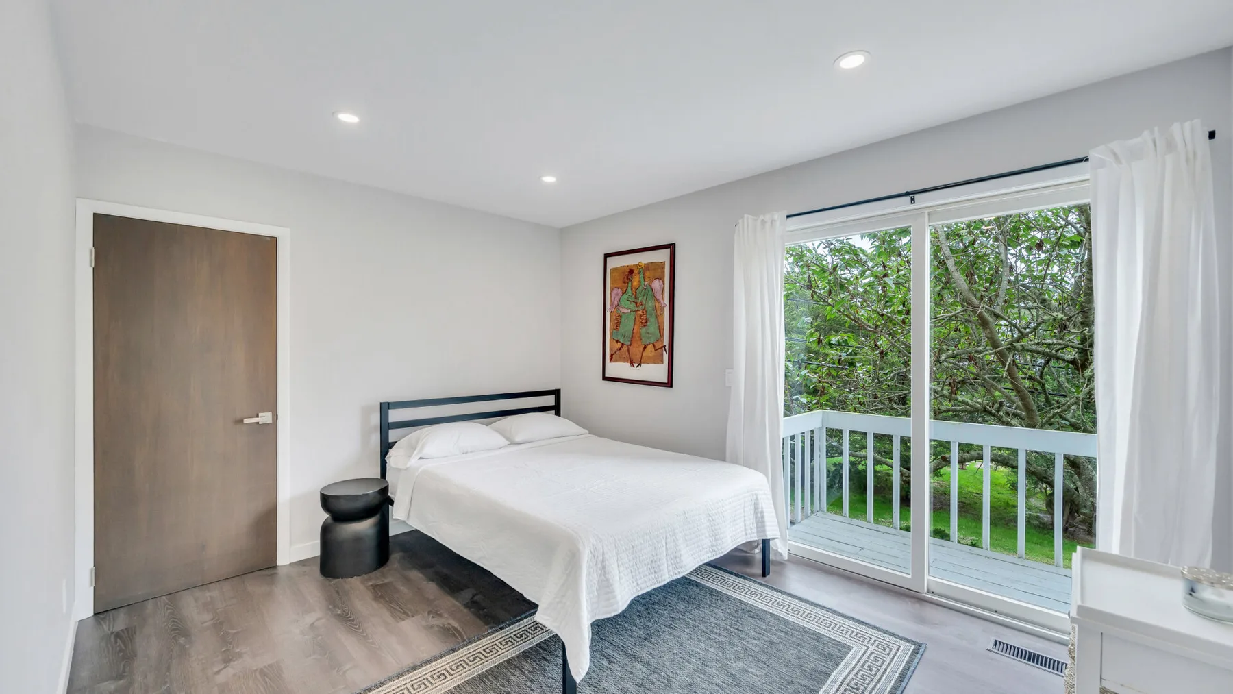 Un dormitorio luminoso con una cama junto a puertas corredizas de vidrio que dan a un balcón.