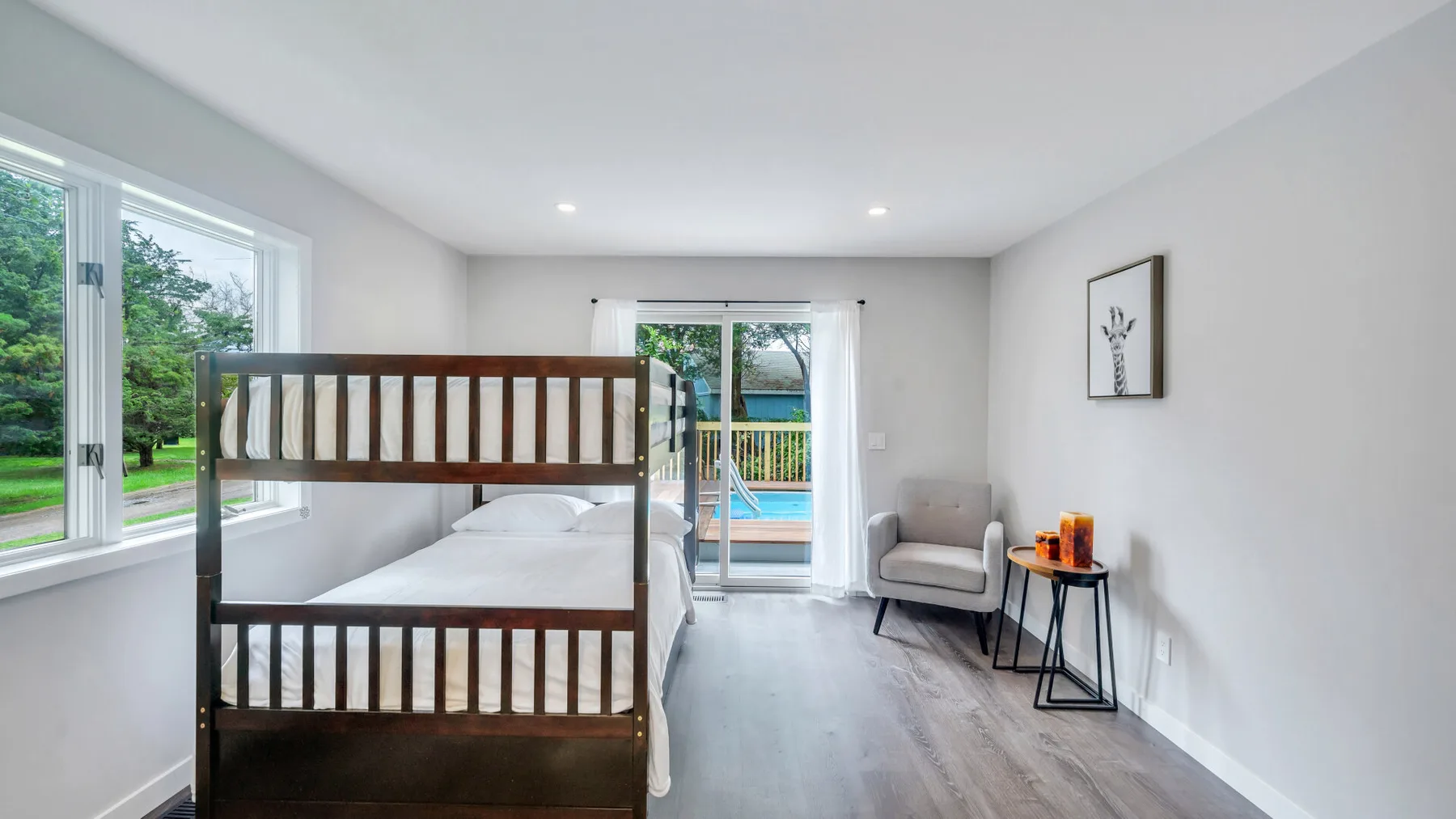 Un dormitorio luminoso con literas y una puerta de cristal que da a un balcón.