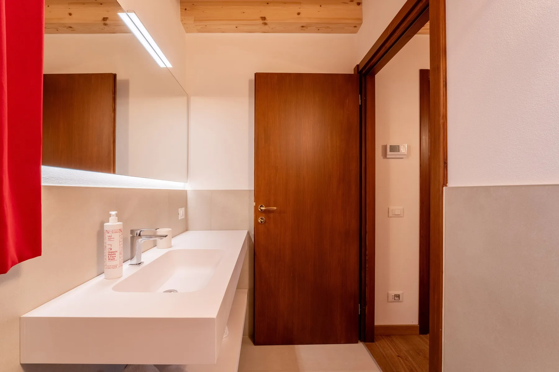 A bathroom with a wide sink counter and a wooden door.