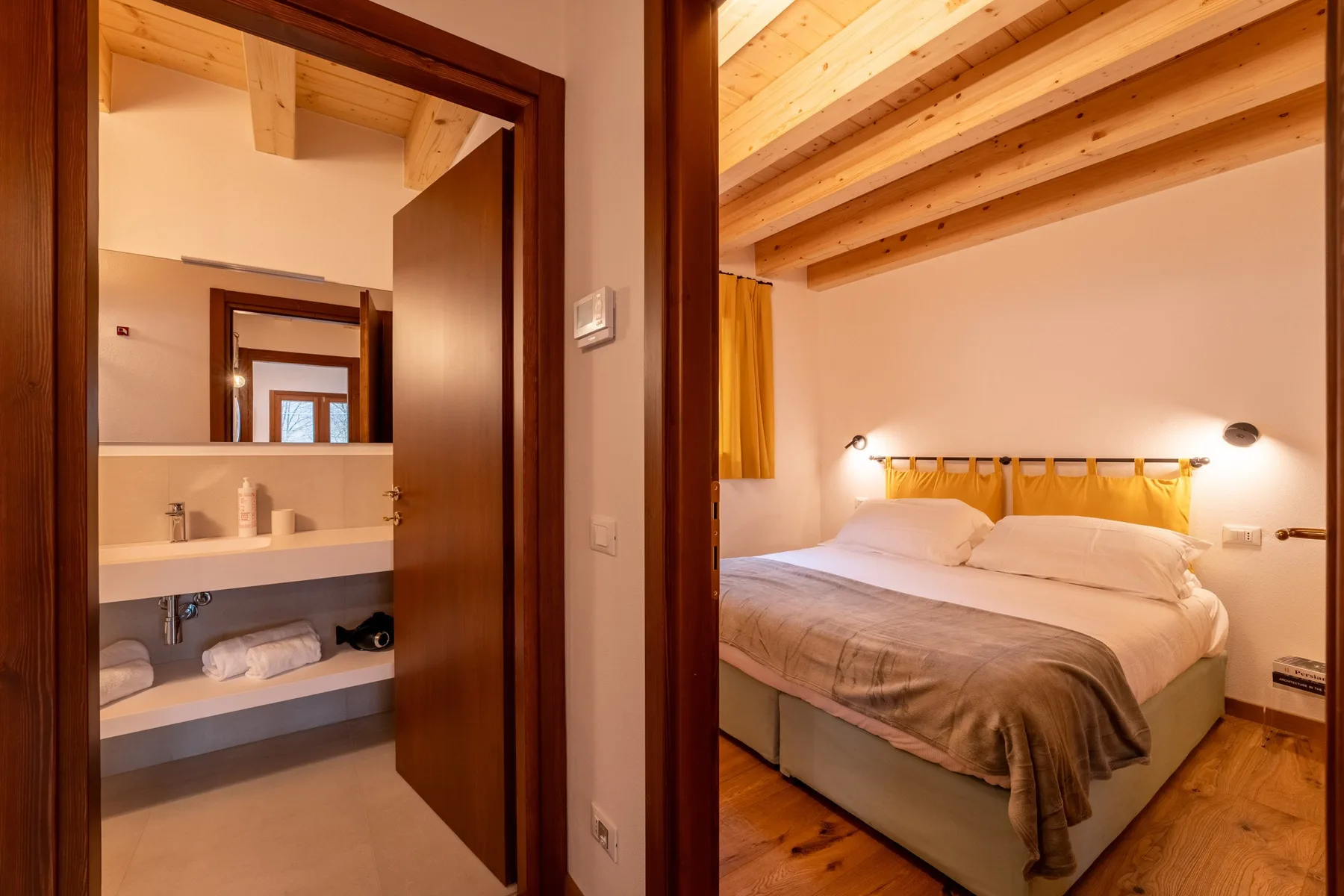 A bedroom with a large bed and a bathroom visible through the doorway.