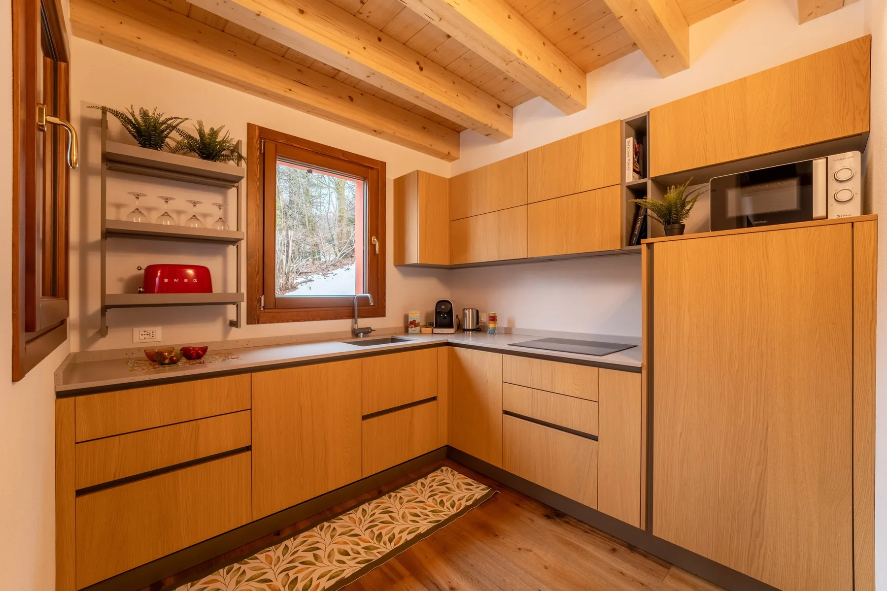 A compact kitchen with wooden cabinets, a countertop, and a window.