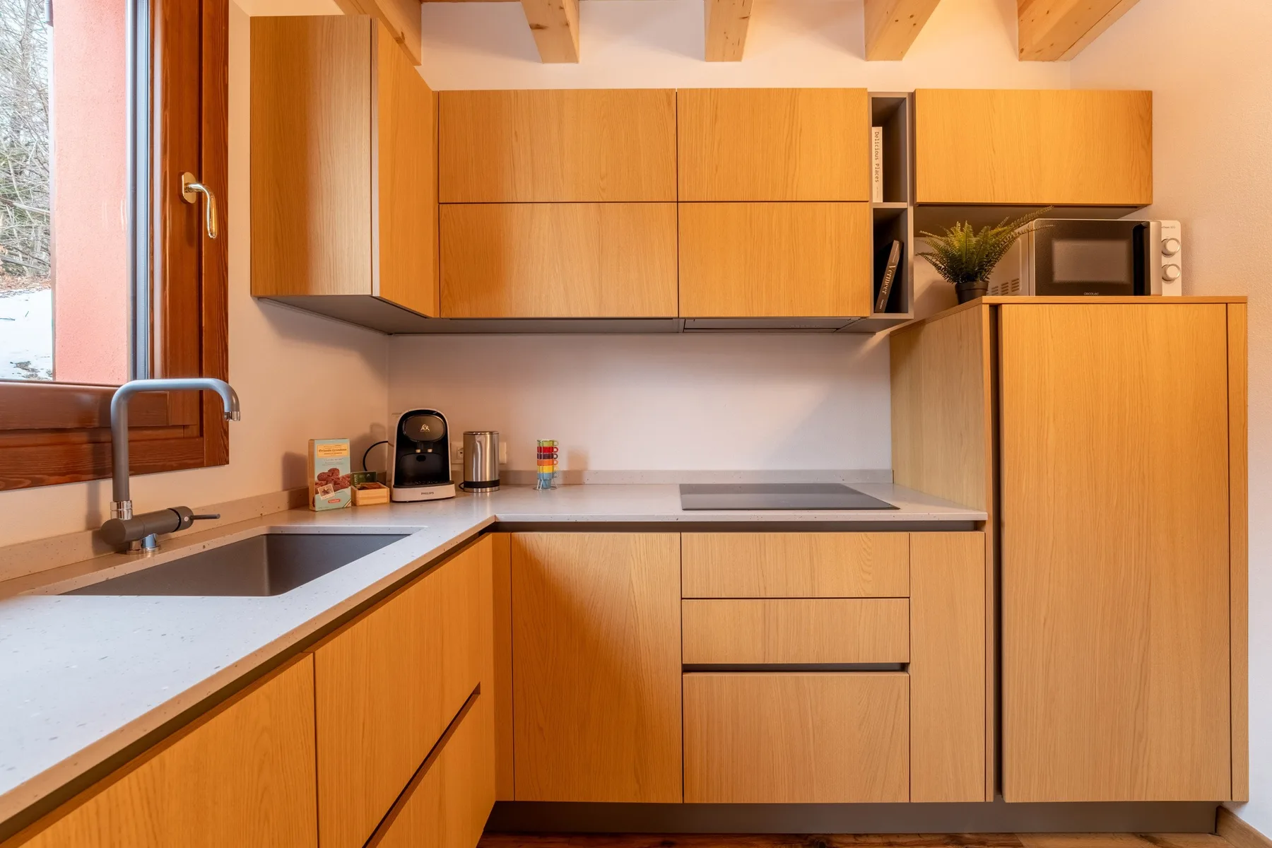 A modern kitchen with wooden cabinetry, a countertop, and a sink.