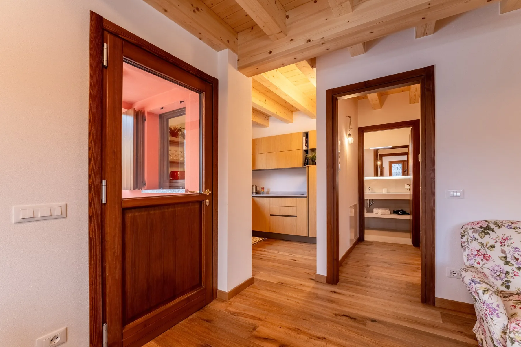 A wood-floored interior hallway opens onto a kitchen and adjoining rooms.
