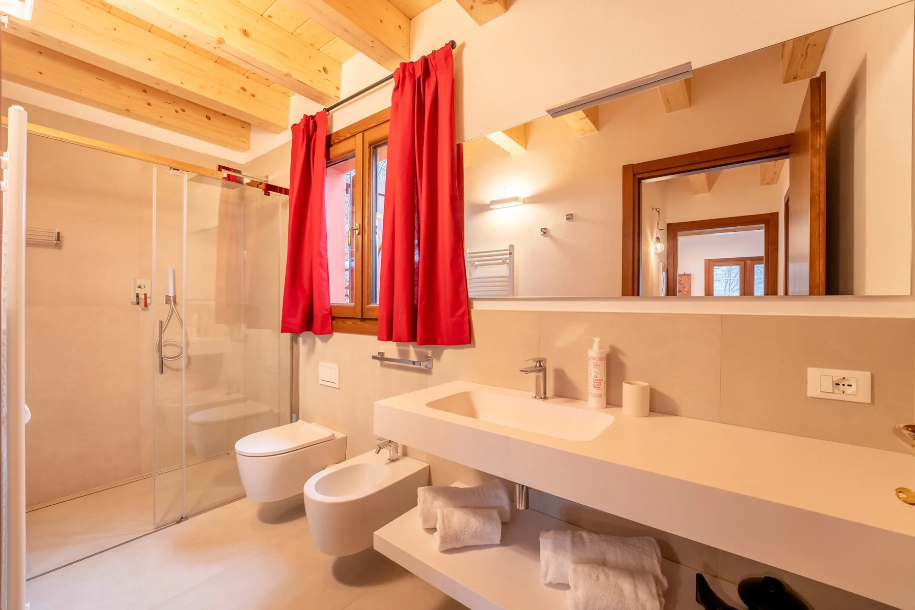 A bright bathroom with a sink, mirror, and glass shower.