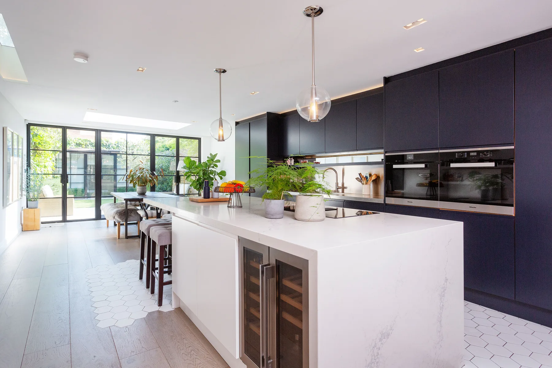 A bright modern kitchen with a large island and dark cabinets.