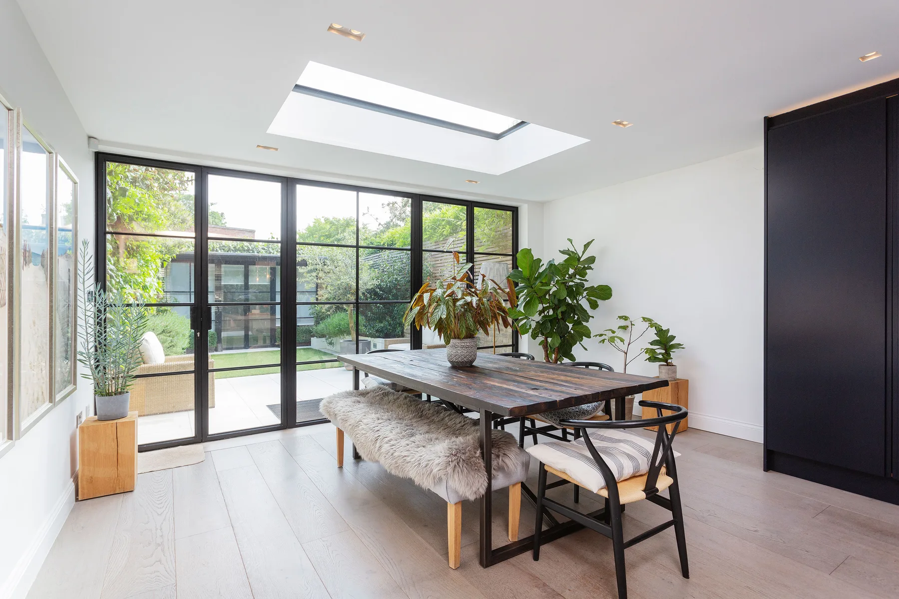 Un comedor luminoso con una mesa larga junto a amplios ventanales con vistas a la vegetación.