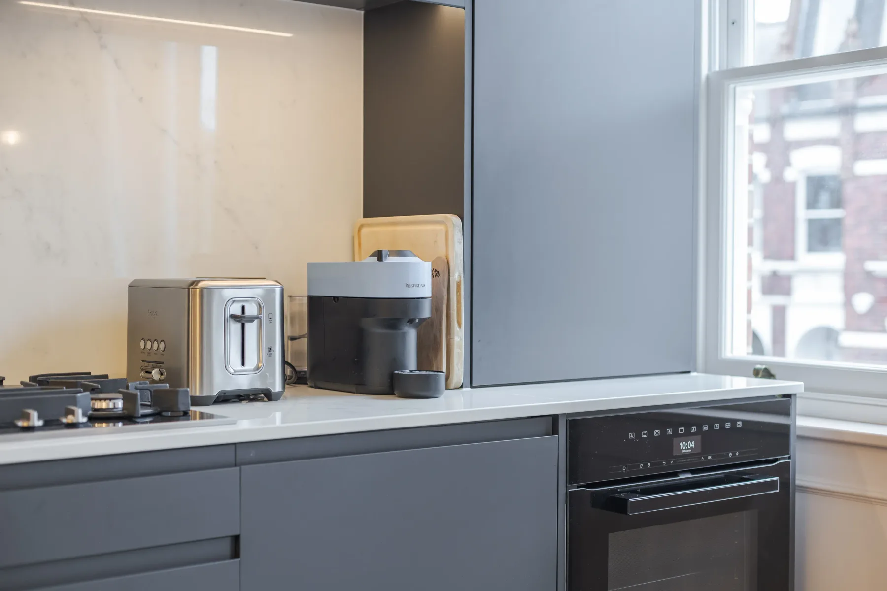 Una encimera de cocina moderna con pequeños electrodomésticos y un horno integrado.