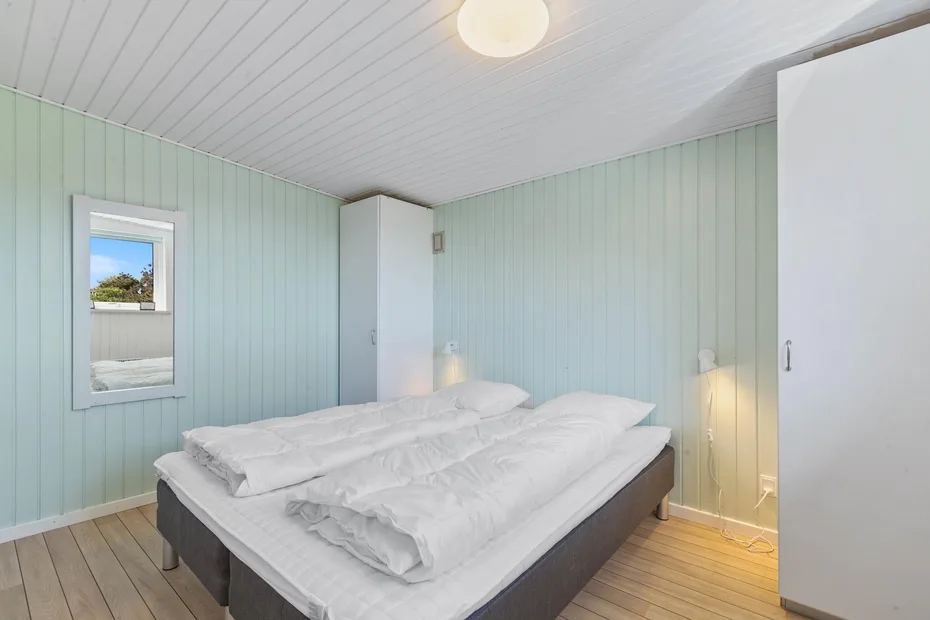 Un dormitorio con una cama vestida con ropa de cama blanca y una ventana pequeña.