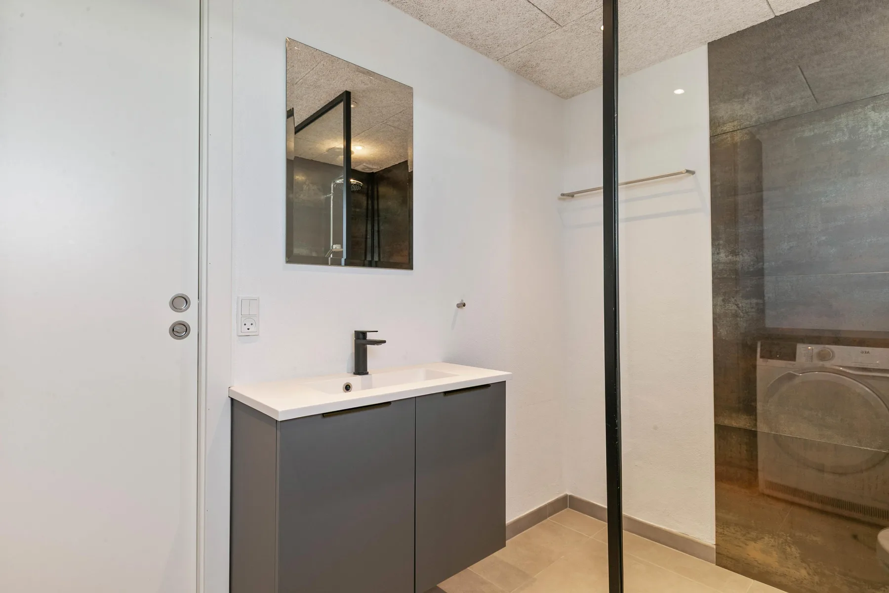 Un baño moderno con lavabo, espejo y ducha.
