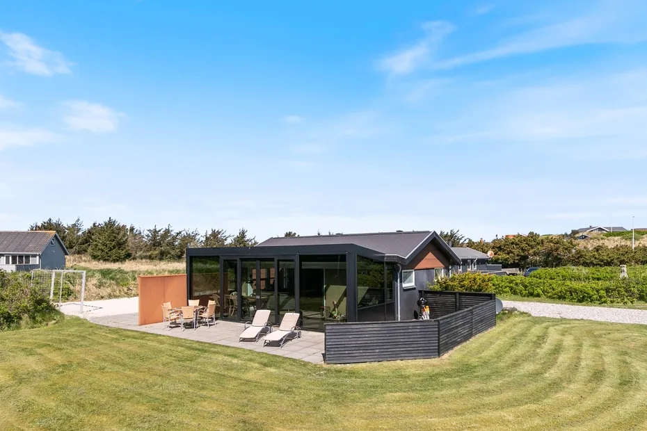 Una casa moderna con una sala acristalada y asientos al aire libre.
