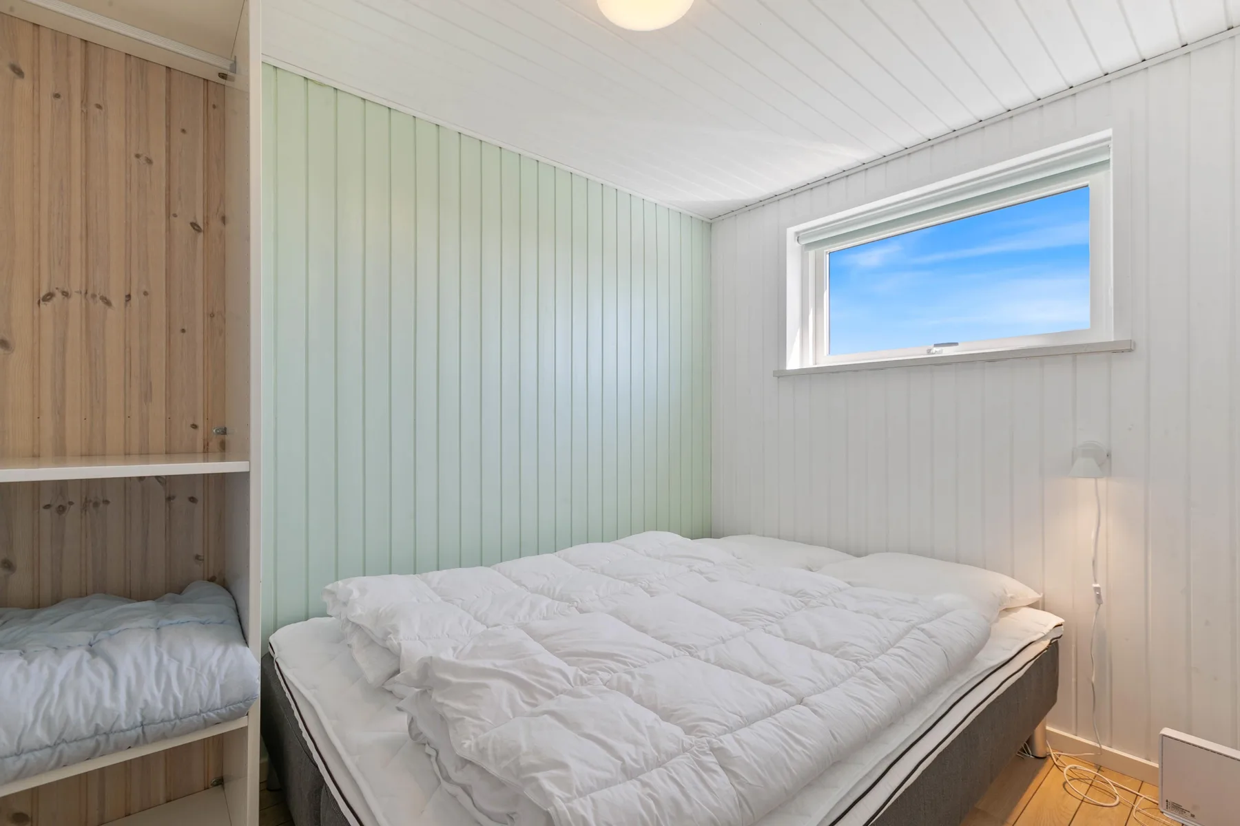 Un dormitorio con una cama debajo de una ventana pequeña.