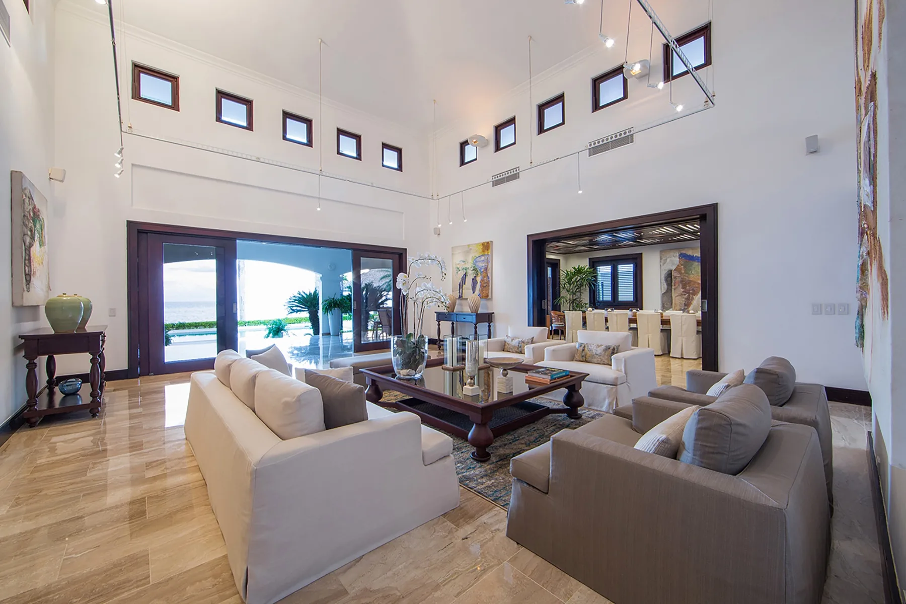 A spacious living room with seating arranged around a coffee table and large windows.