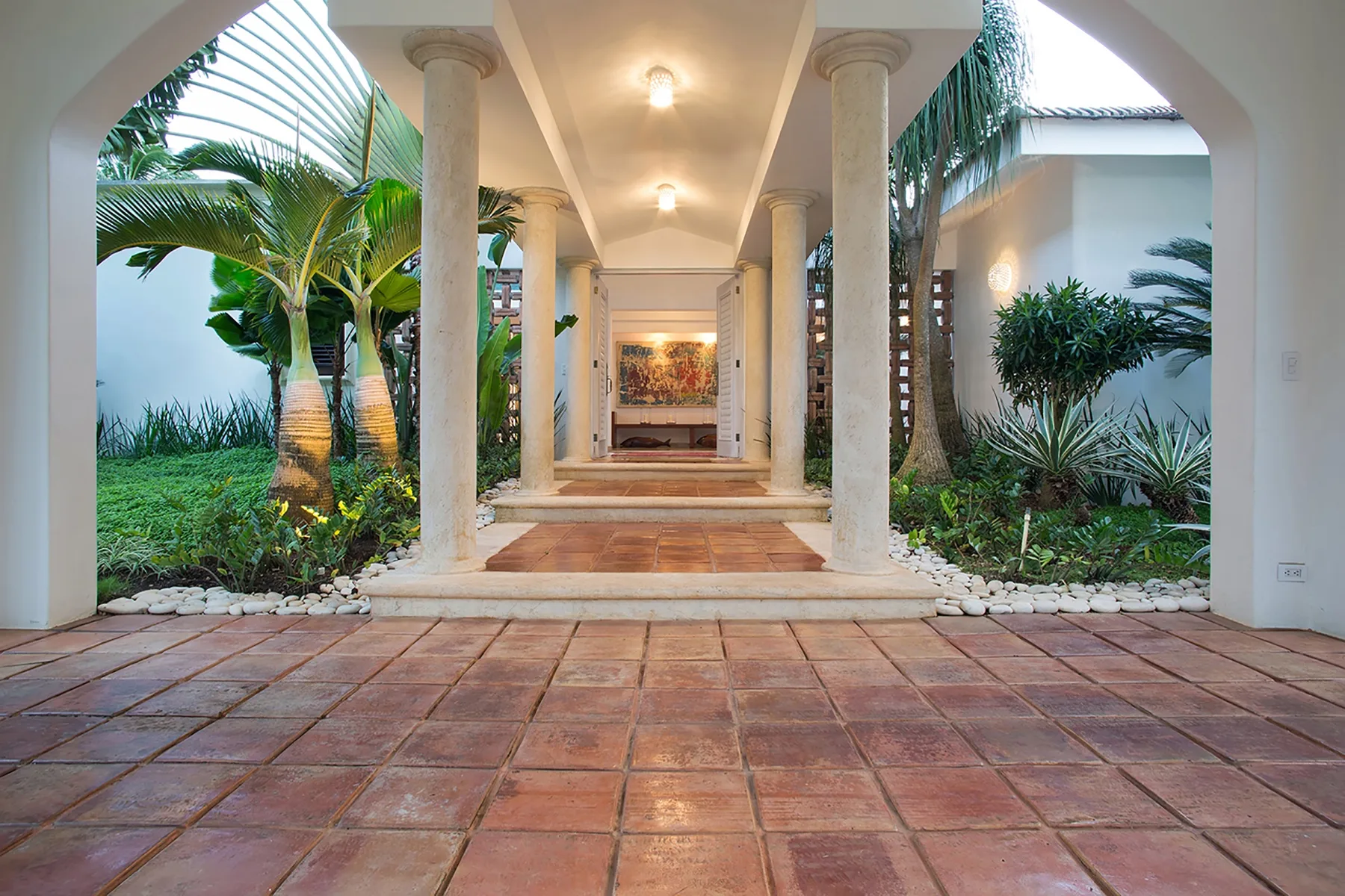 A covered entry walkway with columns opens onto a landscaped courtyard.