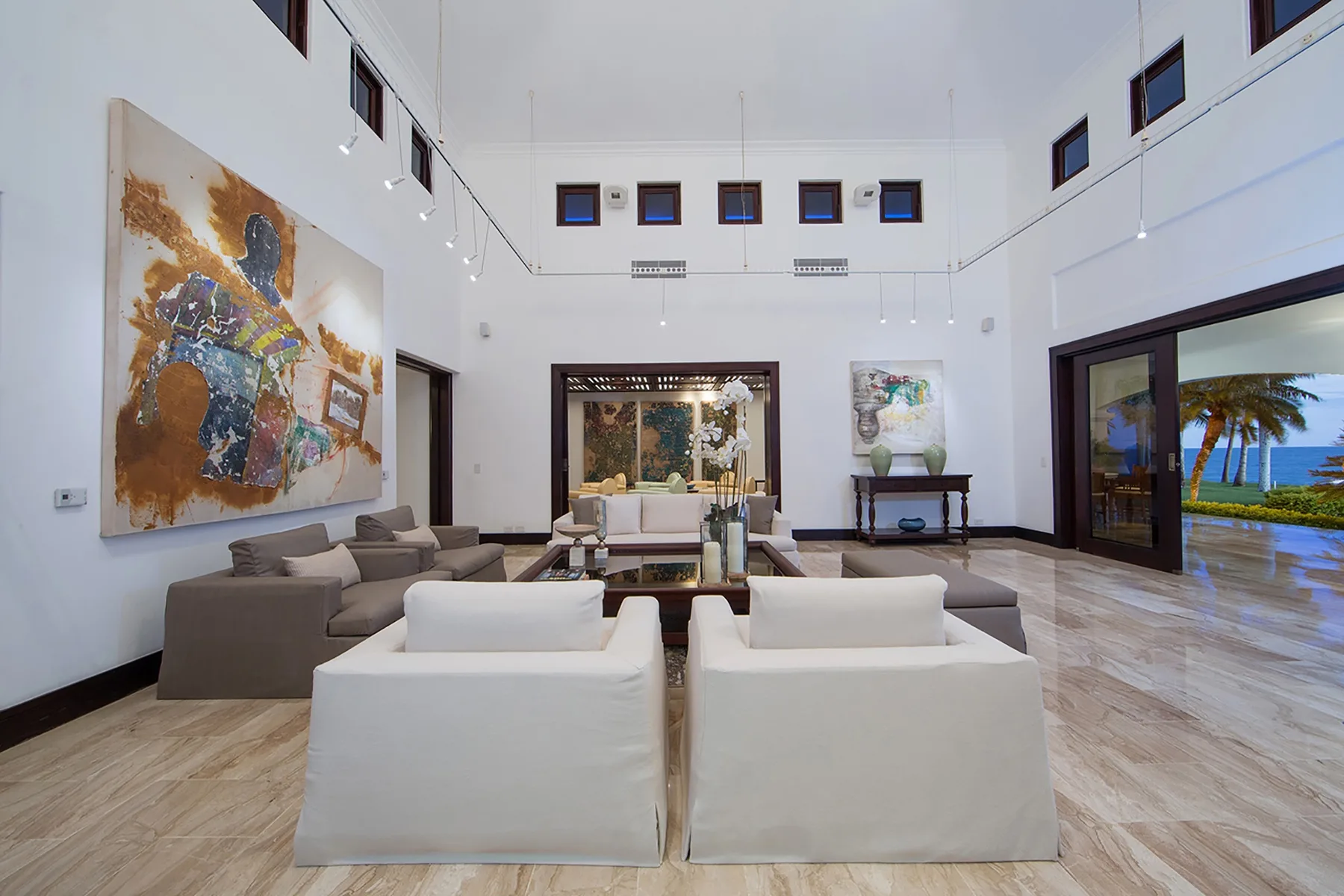 A bright living room with seating arranged around a low table and artwork on the wall.